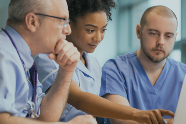 Three doctors look at a laptop