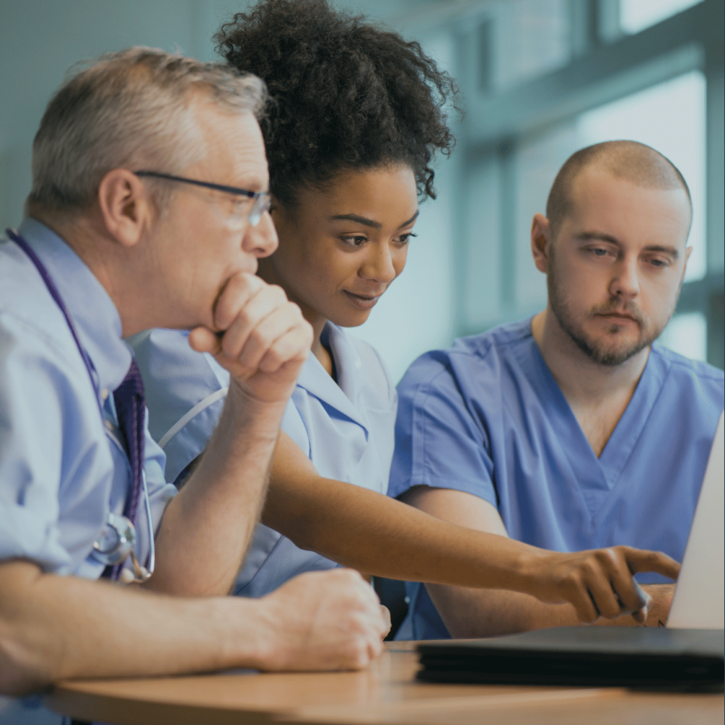 Three doctors look at a laptop